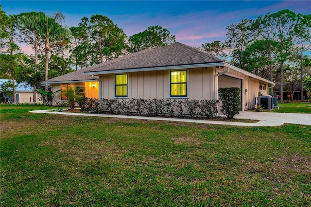 ranch-style home featuring central AC, a garage, and a lawn