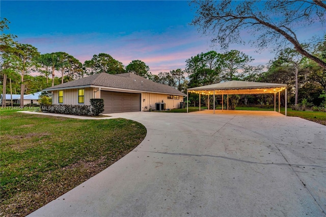 view of front of home featuring cooling unit, a carport, a garage, and a yard