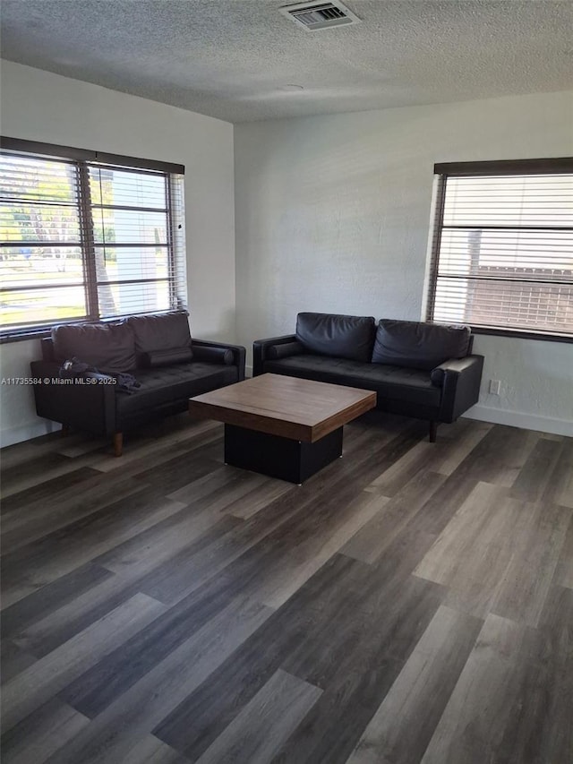 living room featuring dark wood-type flooring and a textured ceiling