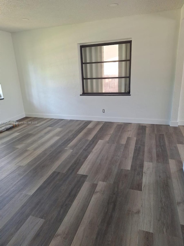 empty room with dark hardwood / wood-style floors and a textured ceiling