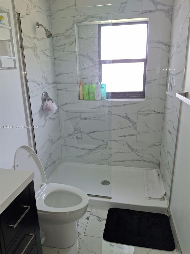 bathroom with vanity, toilet, and tiled shower