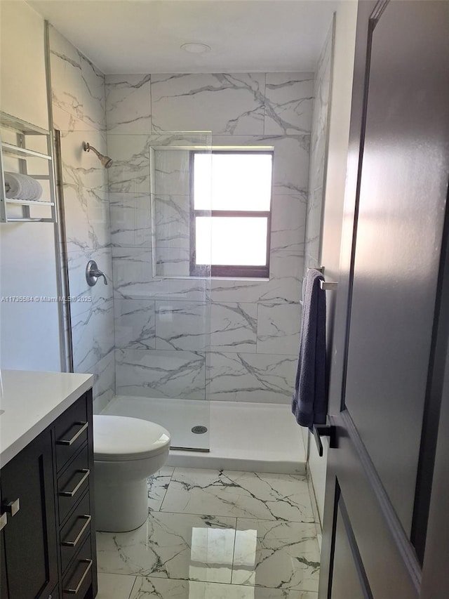 bathroom featuring vanity, tiled shower, and toilet