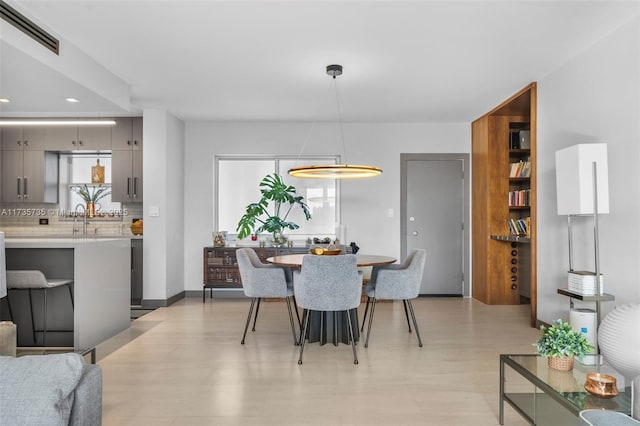 dining room featuring light wood-type flooring, sink, and a wealth of natural light