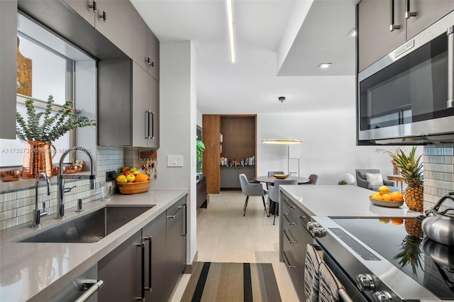 kitchen featuring sink, gray cabinets, appliances with stainless steel finishes, backsplash, and decorative light fixtures