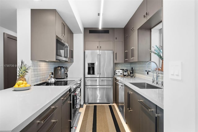 kitchen with tasteful backsplash, stainless steel appliances, gray cabinets, and sink