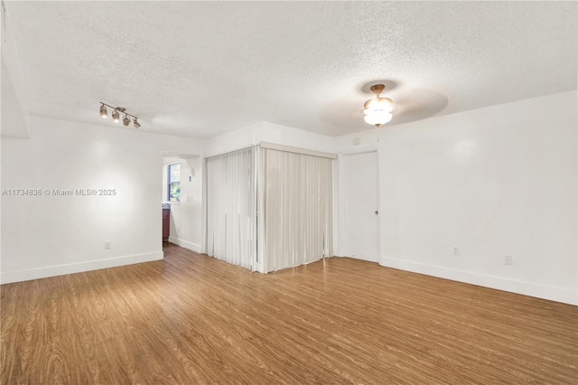 spare room with ceiling fan, wood-type flooring, and a textured ceiling