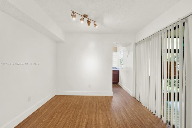 unfurnished room featuring hardwood / wood-style flooring and a textured ceiling