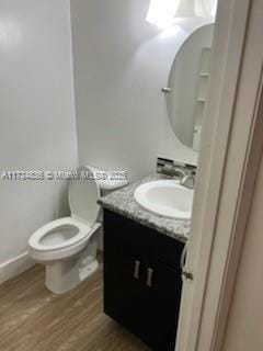 bathroom with hardwood / wood-style flooring, vanity, and toilet