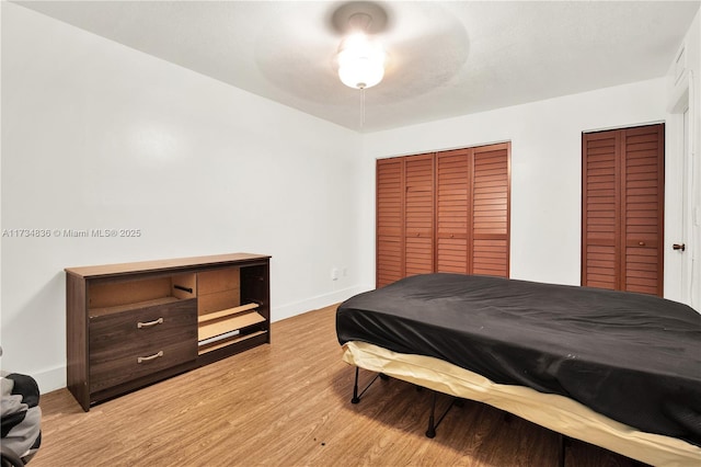 bedroom featuring light hardwood / wood-style flooring, ceiling fan, and two closets