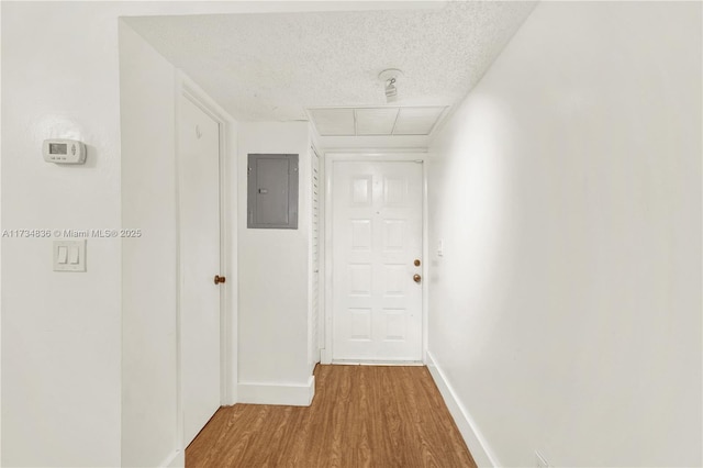 hall with electric panel, a textured ceiling, and hardwood / wood-style floors