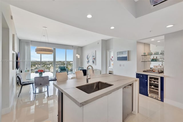 kitchen featuring white cabinetry, sink, beverage cooler, and an island with sink