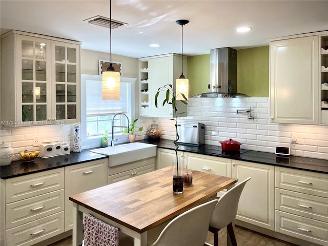 kitchen with sink, pendant lighting, backsplash, and wall chimney exhaust hood