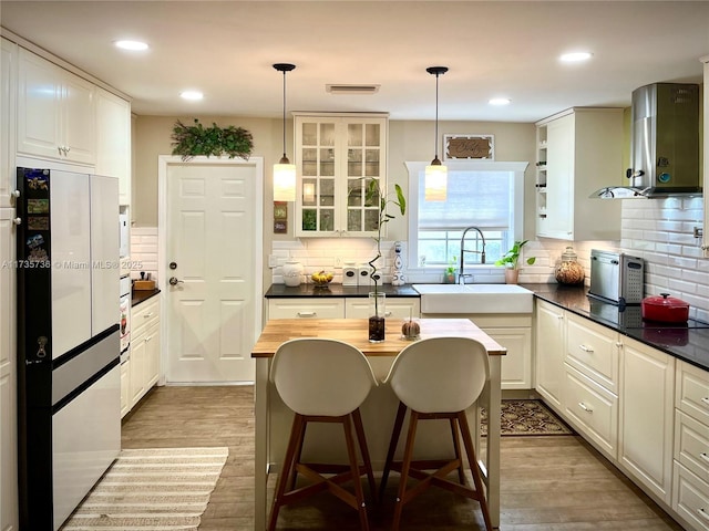 kitchen with sink, a breakfast bar area, white cabinetry, light hardwood / wood-style flooring, and pendant lighting