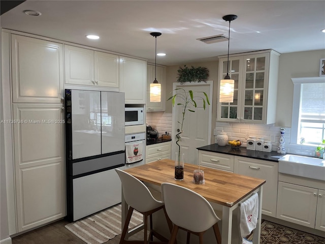 kitchen with decorative light fixtures, tasteful backsplash, white cabinetry, sink, and white appliances