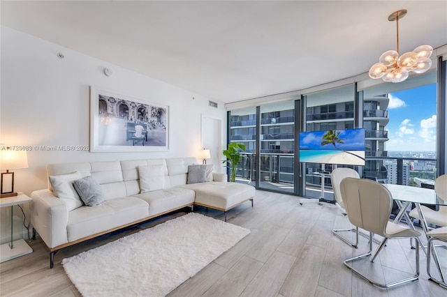 living room with expansive windows, a chandelier, and light hardwood / wood-style floors