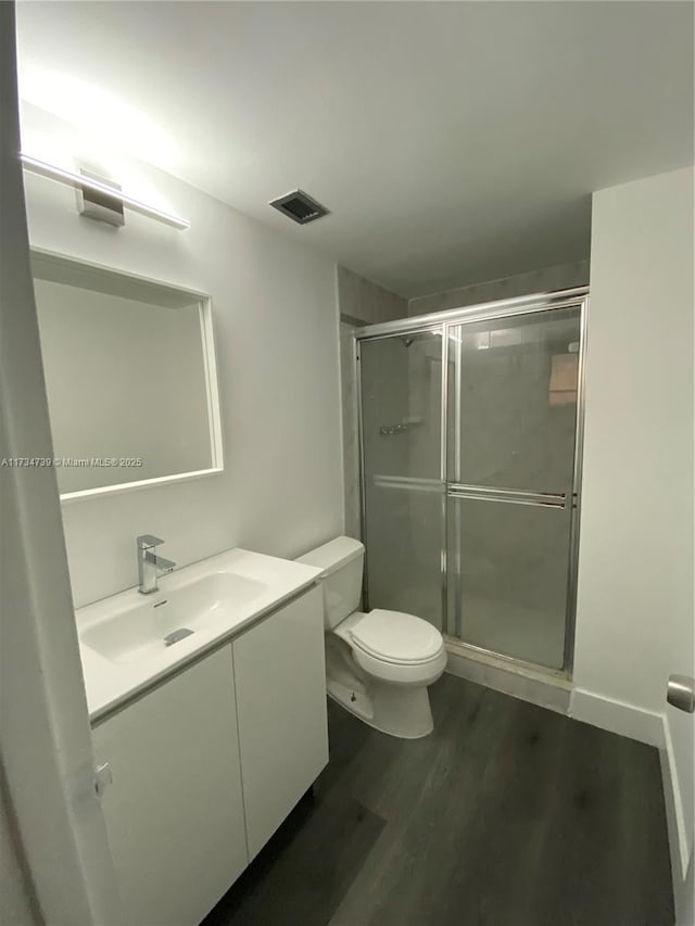 bathroom with vanity, hardwood / wood-style floors, walk in shower, and toilet