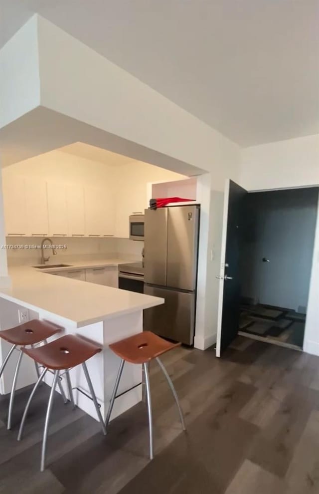 kitchen with sink, a breakfast bar area, stainless steel appliances, and kitchen peninsula