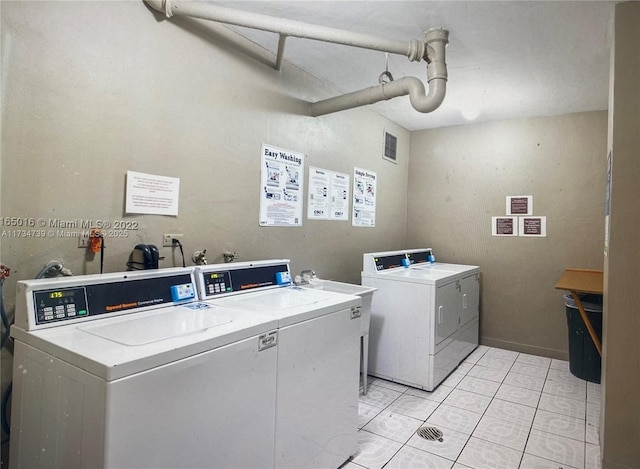 clothes washing area featuring light tile patterned floors and washer and clothes dryer