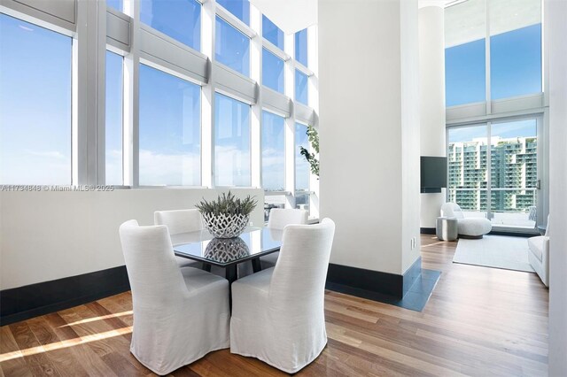 dining area featuring a towering ceiling and wood-type flooring