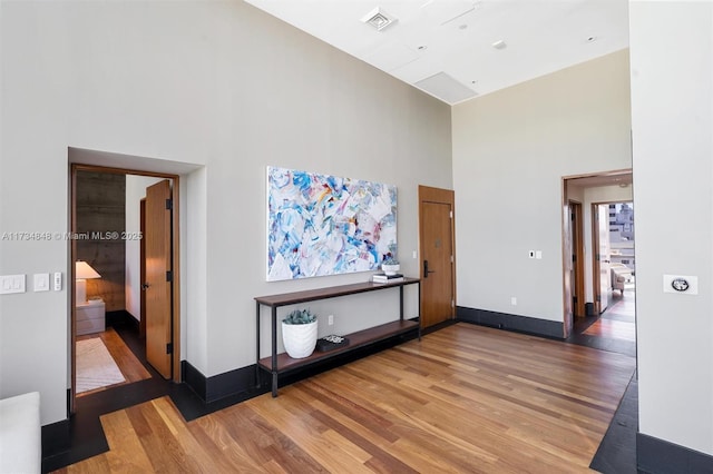 hall with hardwood / wood-style floors and a towering ceiling