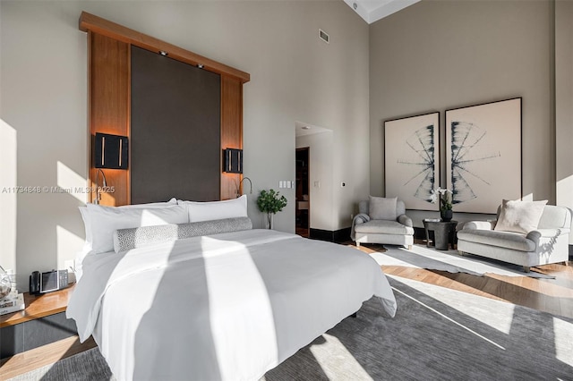 bedroom with hardwood / wood-style flooring and a high ceiling