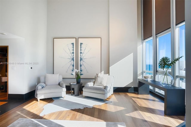 sitting room with a towering ceiling and wood-type flooring