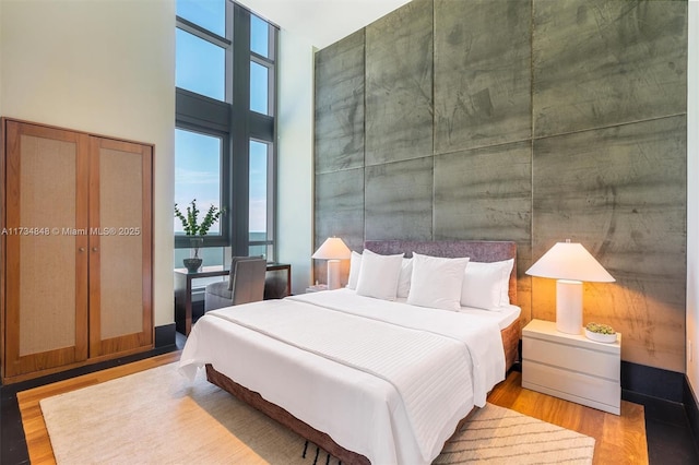 bedroom featuring wood-type flooring and a high ceiling