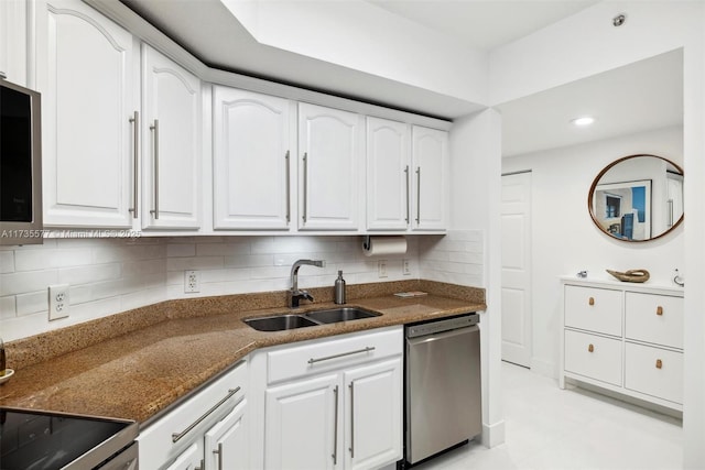 kitchen with dark stone countertops, stainless steel appliances, sink, and white cabinets