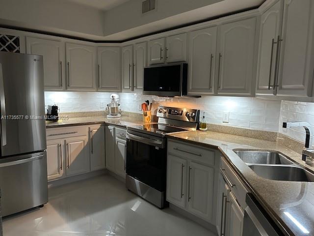 kitchen featuring stainless steel appliances, tasteful backsplash, sink, and stone counters