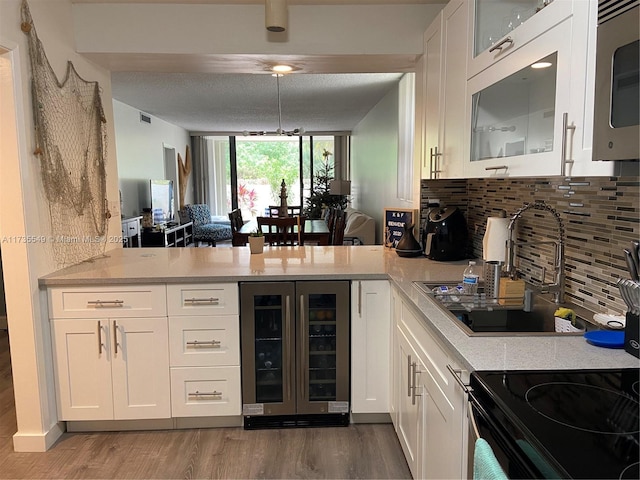 kitchen featuring white cabinetry, wood-type flooring, beverage cooler, and backsplash