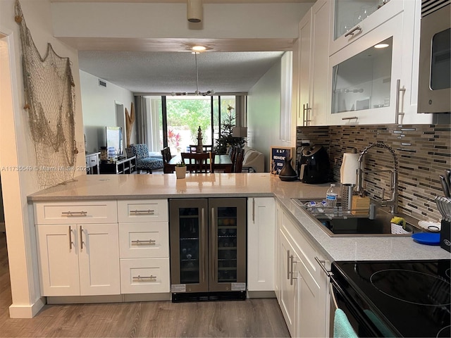 kitchen with wine cooler, white cabinetry, decorative backsplash, and hardwood / wood-style flooring