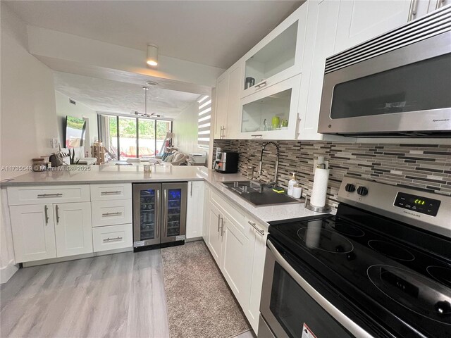 kitchen with sink, appliances with stainless steel finishes, backsplash, white cabinets, and beverage cooler