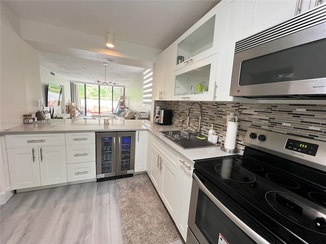 kitchen featuring sink, appliances with stainless steel finishes, beverage cooler, decorative backsplash, and white cabinets