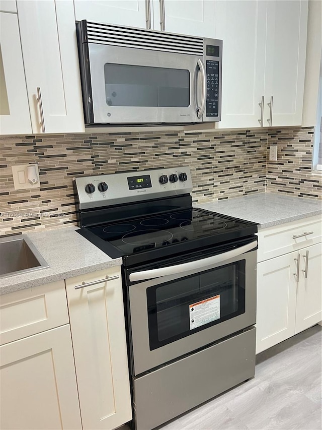 kitchen featuring tasteful backsplash, stainless steel appliances, light stone countertops, and white cabinets