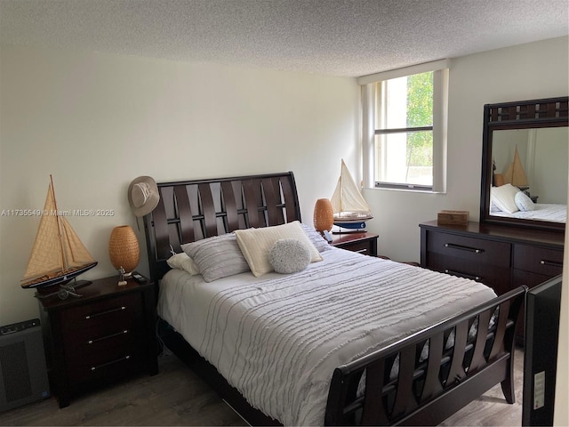 bedroom featuring wood-type flooring, radiator heating unit, and a textured ceiling