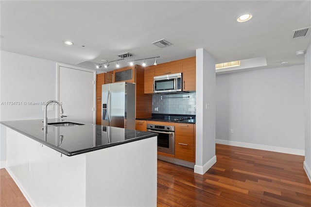 kitchen with sink, dark wood-type flooring, a breakfast bar, stainless steel appliances, and decorative backsplash