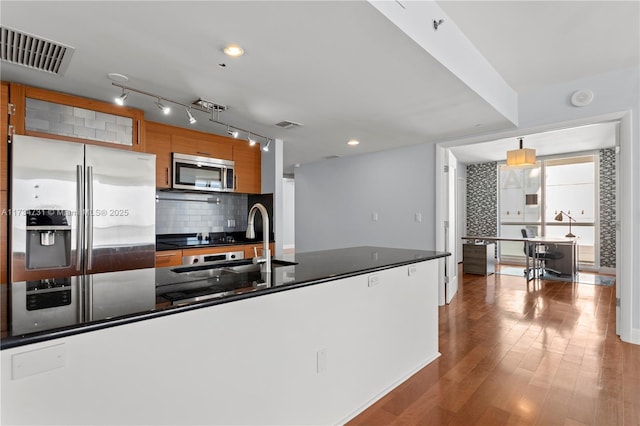 kitchen featuring sink, wood-type flooring, appliances with stainless steel finishes, pendant lighting, and backsplash