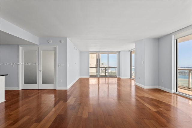 unfurnished room featuring a healthy amount of sunlight, floor to ceiling windows, and wood-type flooring