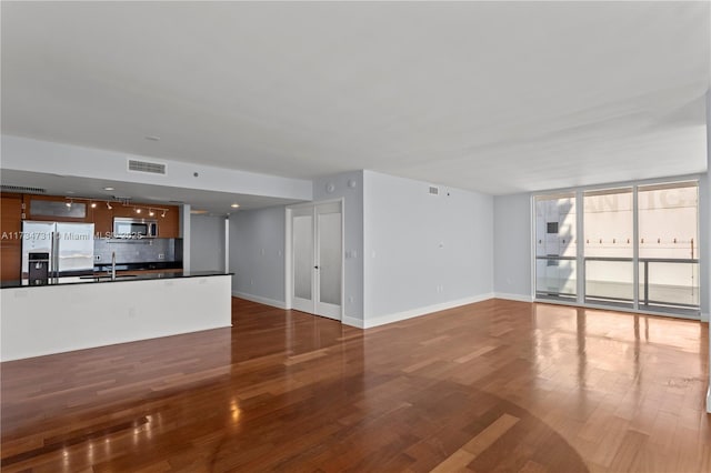 unfurnished living room featuring sink, wood-type flooring, and expansive windows