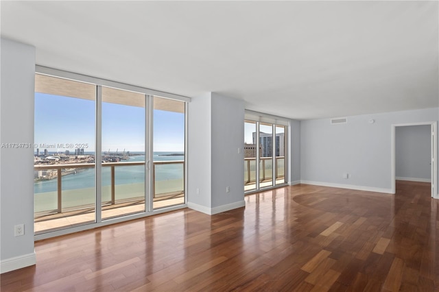 spare room featuring a water view, expansive windows, and hardwood / wood-style flooring