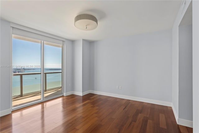 spare room featuring wood-type flooring, floor to ceiling windows, and a water view