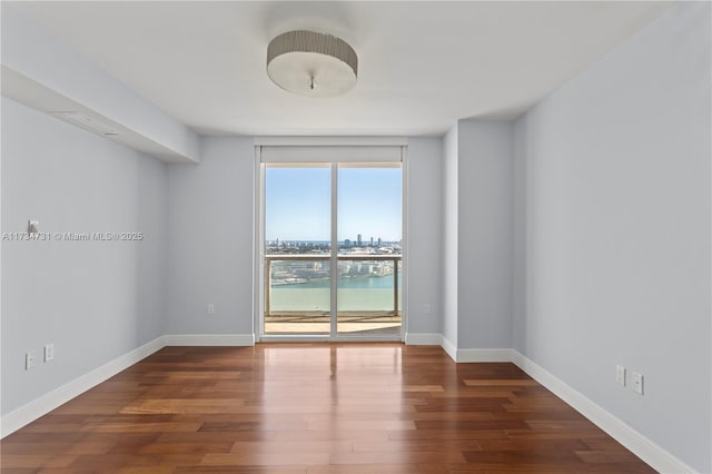 spare room with a water view and dark wood-type flooring