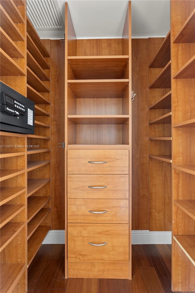 walk in closet with dark wood-type flooring