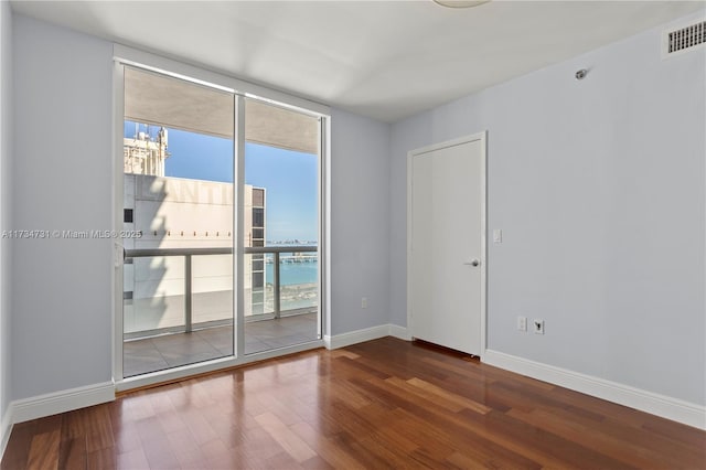 empty room featuring a wall of windows, wood-type flooring, and a water view