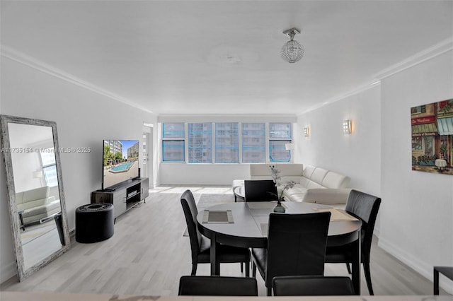 dining space featuring ornamental molding and light hardwood / wood-style flooring