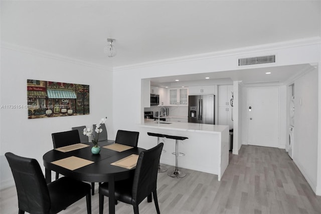 dining room featuring ornamental molding, washer / dryer, sink, and light hardwood / wood-style flooring