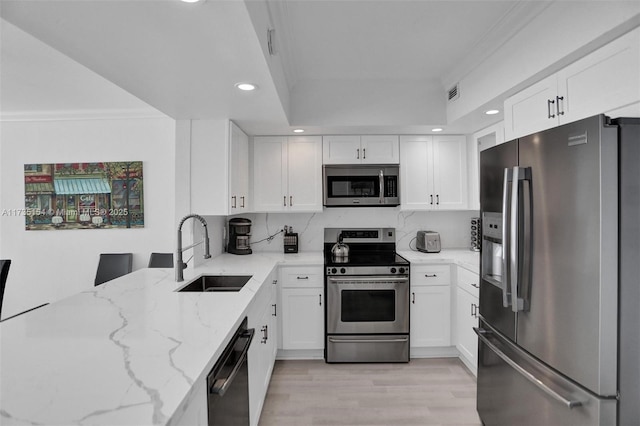 kitchen featuring light stone counters, white cabinetry, appliances with stainless steel finishes, and sink