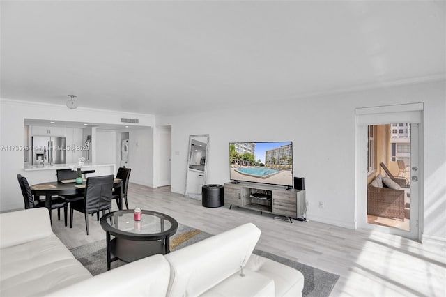 living room featuring crown molding and light hardwood / wood-style floors