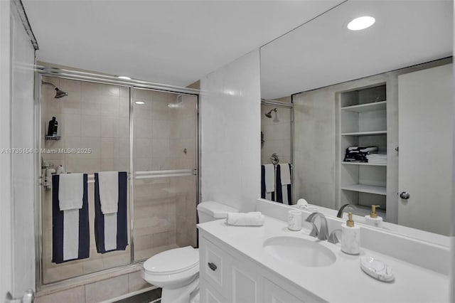 bathroom with vanity, built in shelves, toilet, and walk in shower