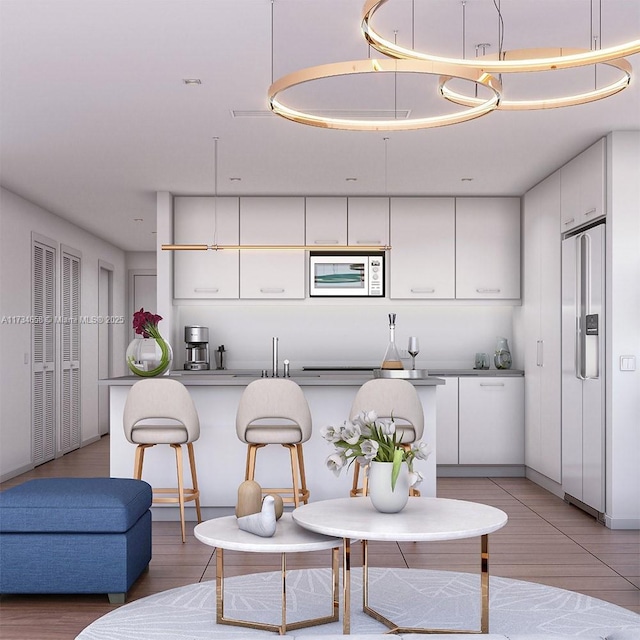 kitchen featuring white cabinetry, decorative light fixtures, hardwood / wood-style flooring, and paneled built in refrigerator